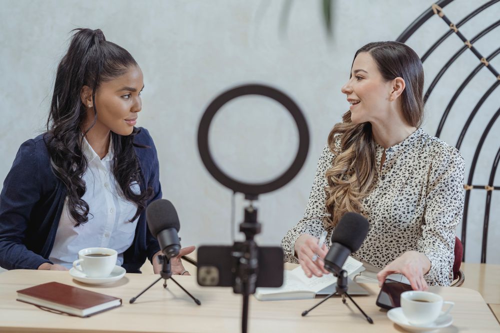 An interviewer recording a lively conversation with a speaker on camera